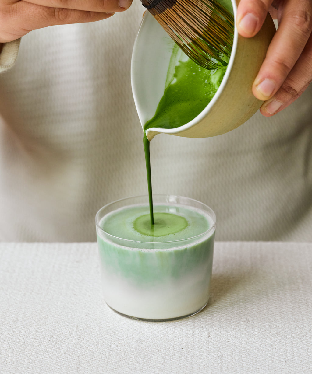 Pouring Matcha Kakegawa latte into glass with steamed milk