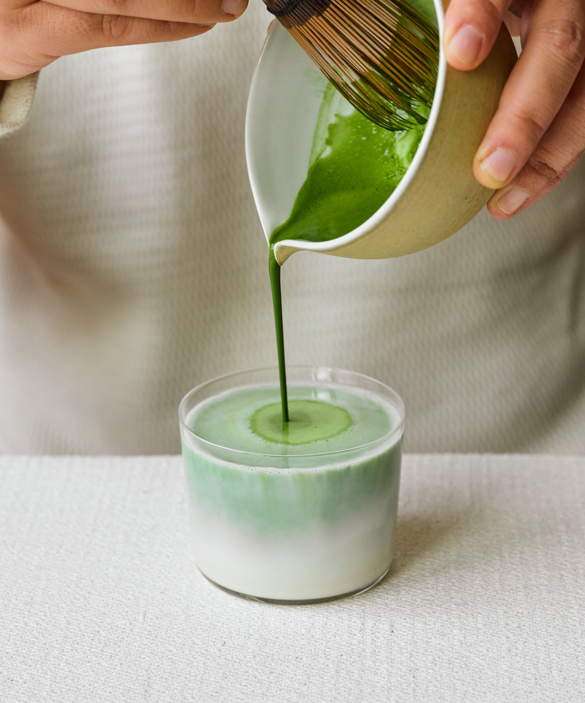 Pouring Matcha Kakegawa latte into glass with steamed milk