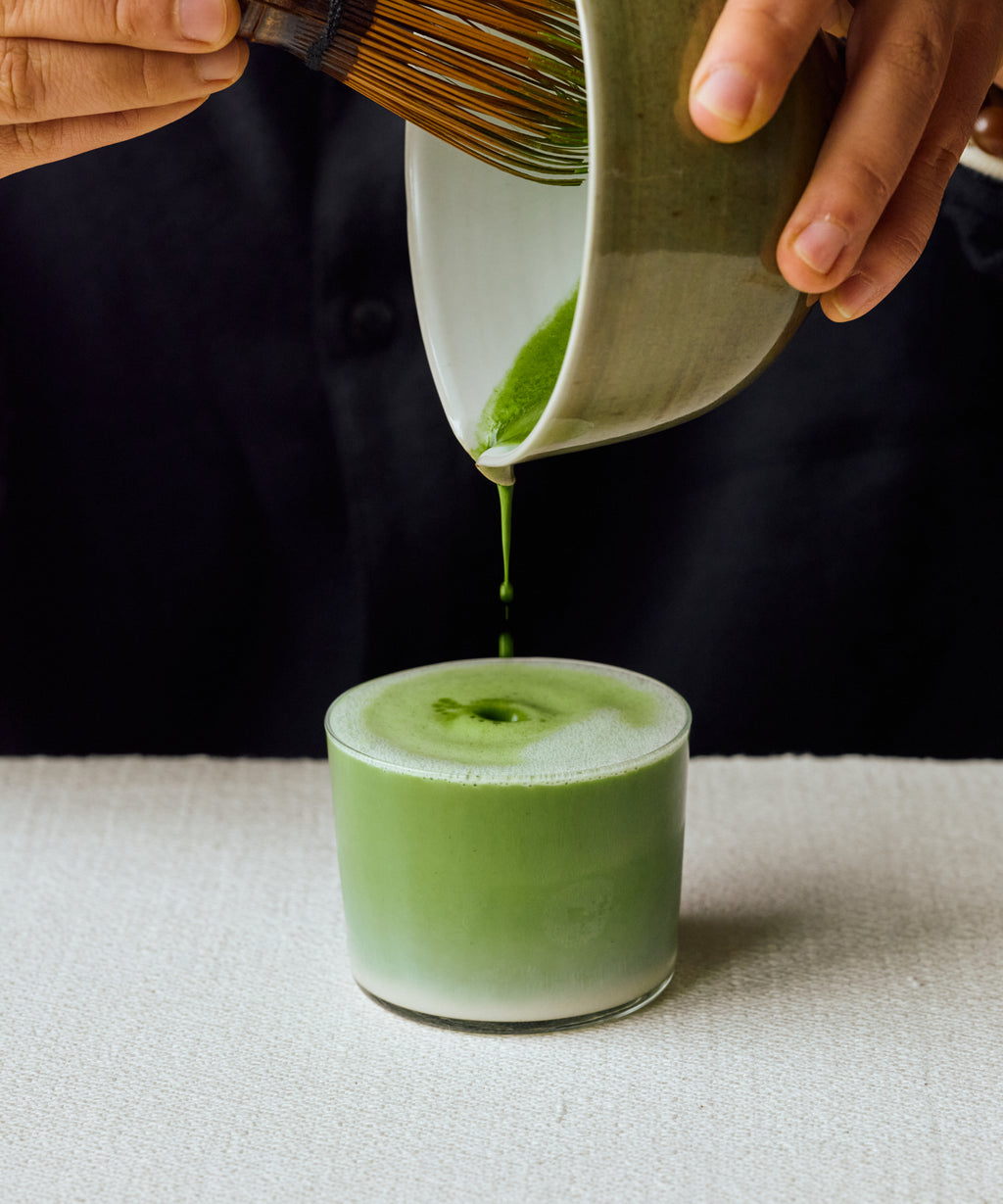 Pouring Matcha Yamekaze latte into glass with steamed milk