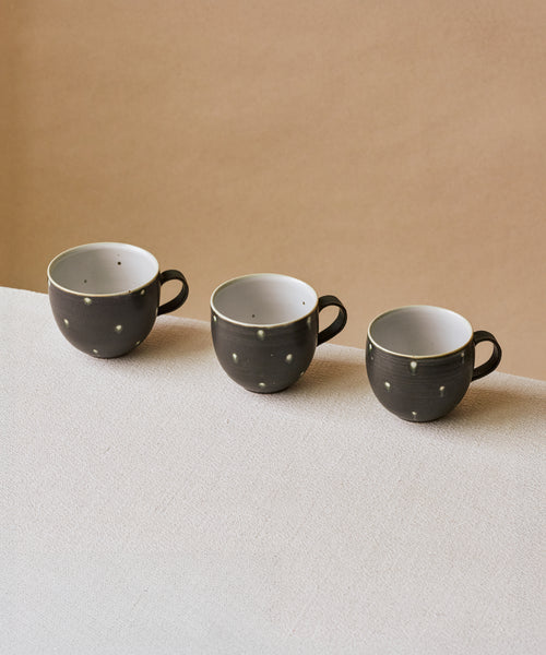 Black Peacock Mug in hand, matte midnight glaze with peacock markings, Wang Xinghua ceramics, Jingdezhen