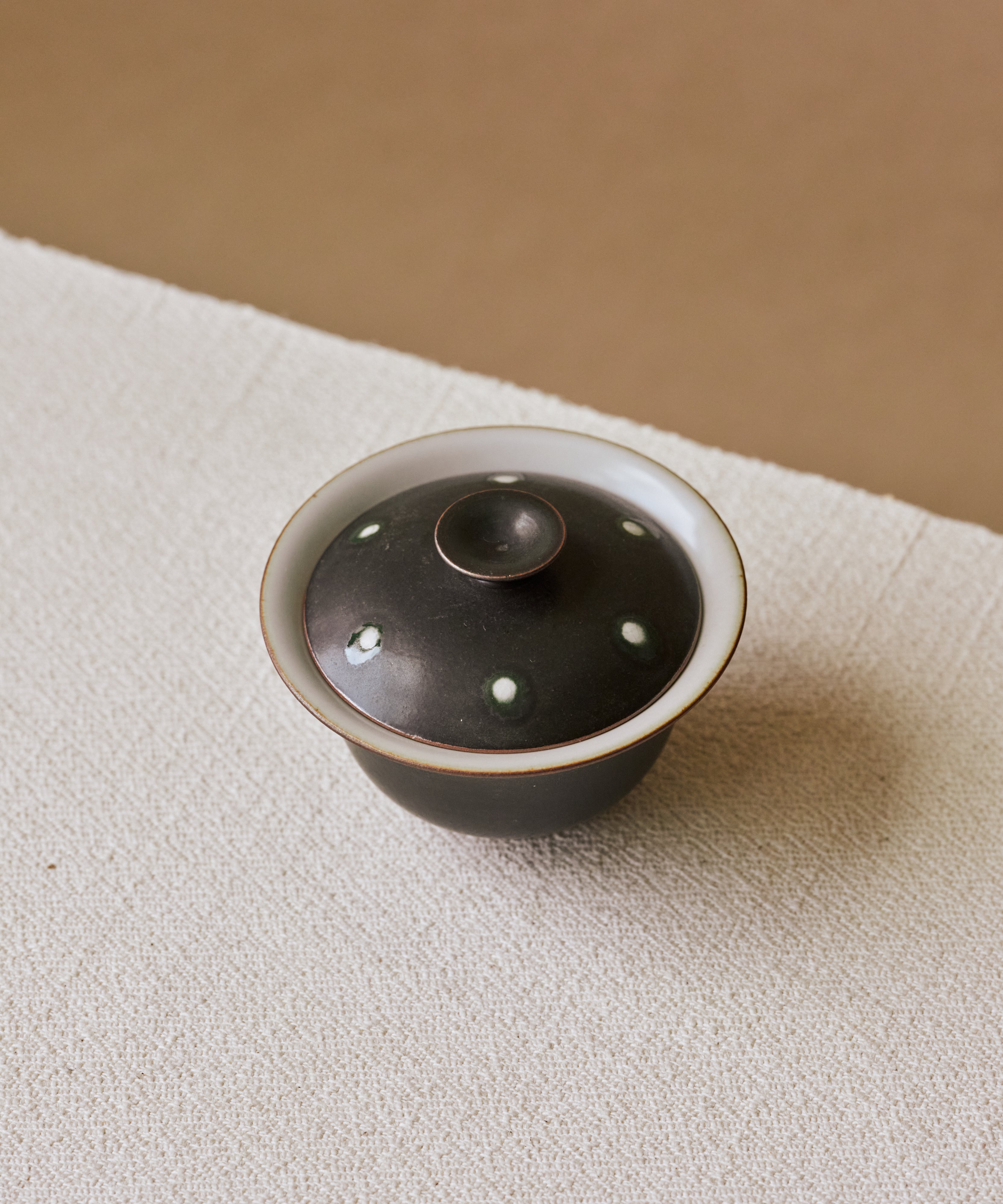 Gaiwan Black Peacock in hand, peacock-iris pattern on matte black, Wang Xinghua gongfu teaware