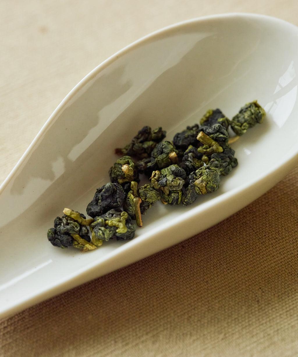 Cuifeng High Mountain rolled oolong on white dish — high-altitude Taiwanese oolong with cold fragrance and dissolved sugar sweetness