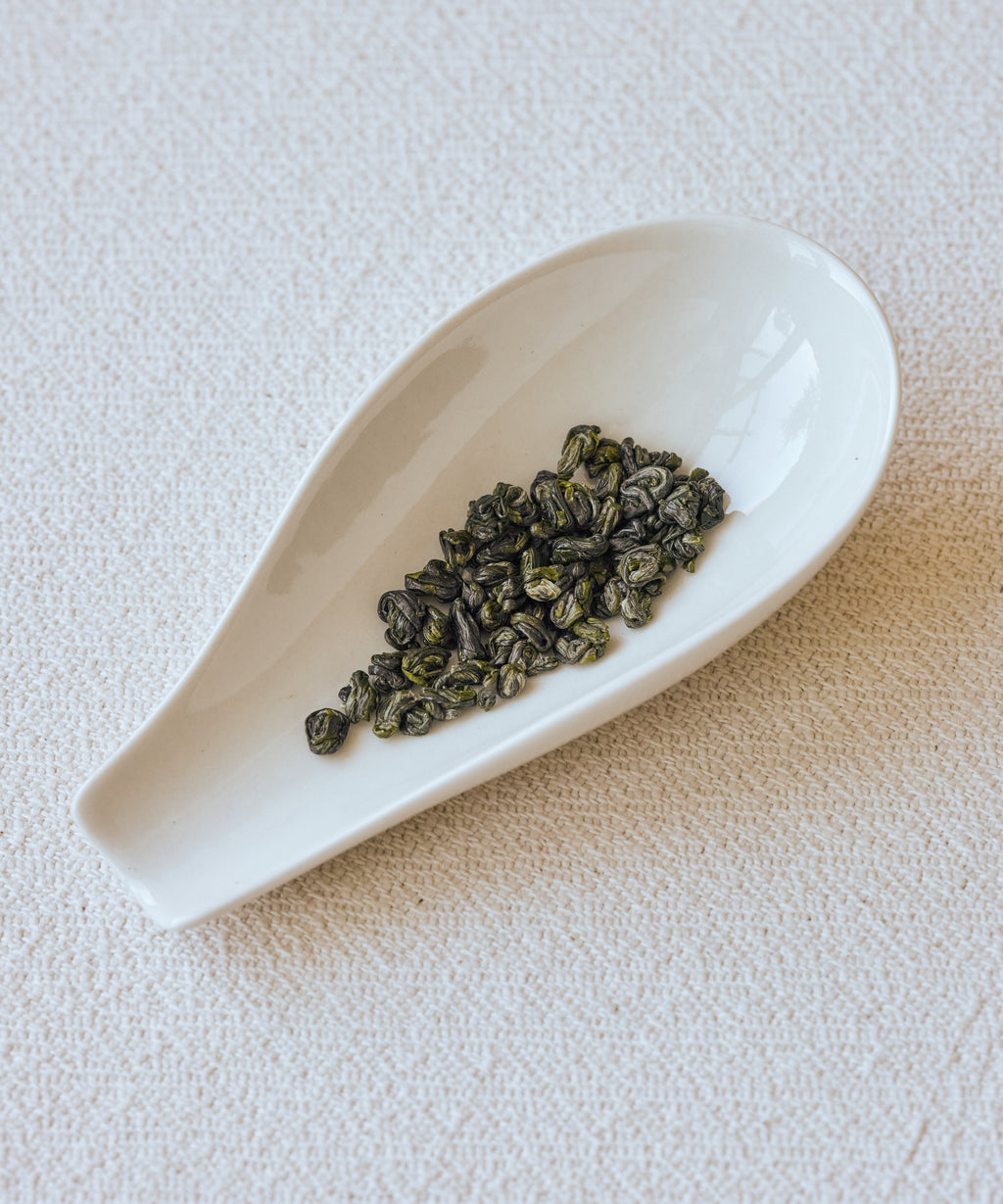 Huoqing Fire Jade tightly rolled leaves on white dish — Mr. Zhu's 20-hour charcoal pan-fried green tea