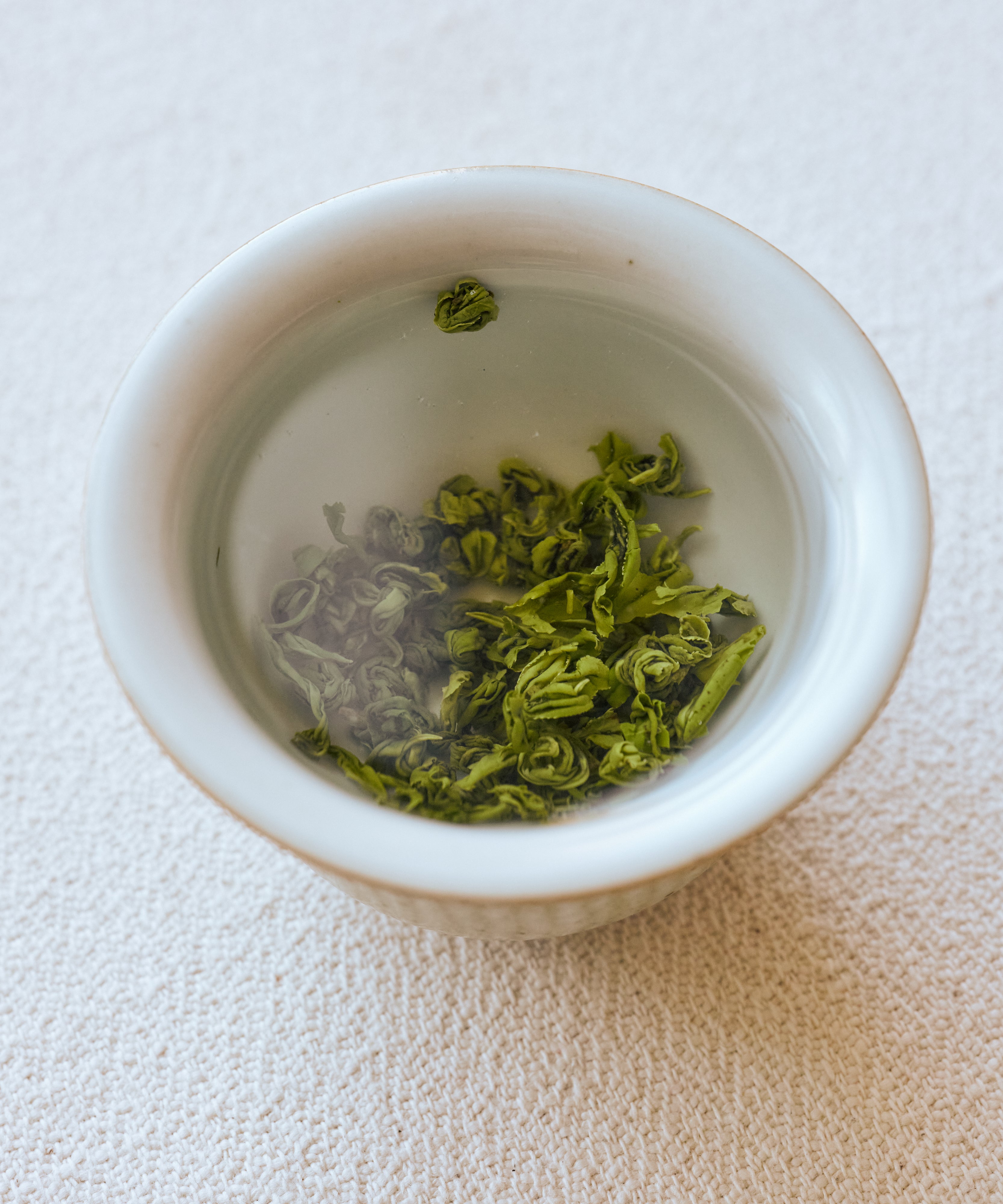 Huoqing Fire Jade wet leaves in bowl — bright youthful leaves unfurled after 20 hours of pan-frying