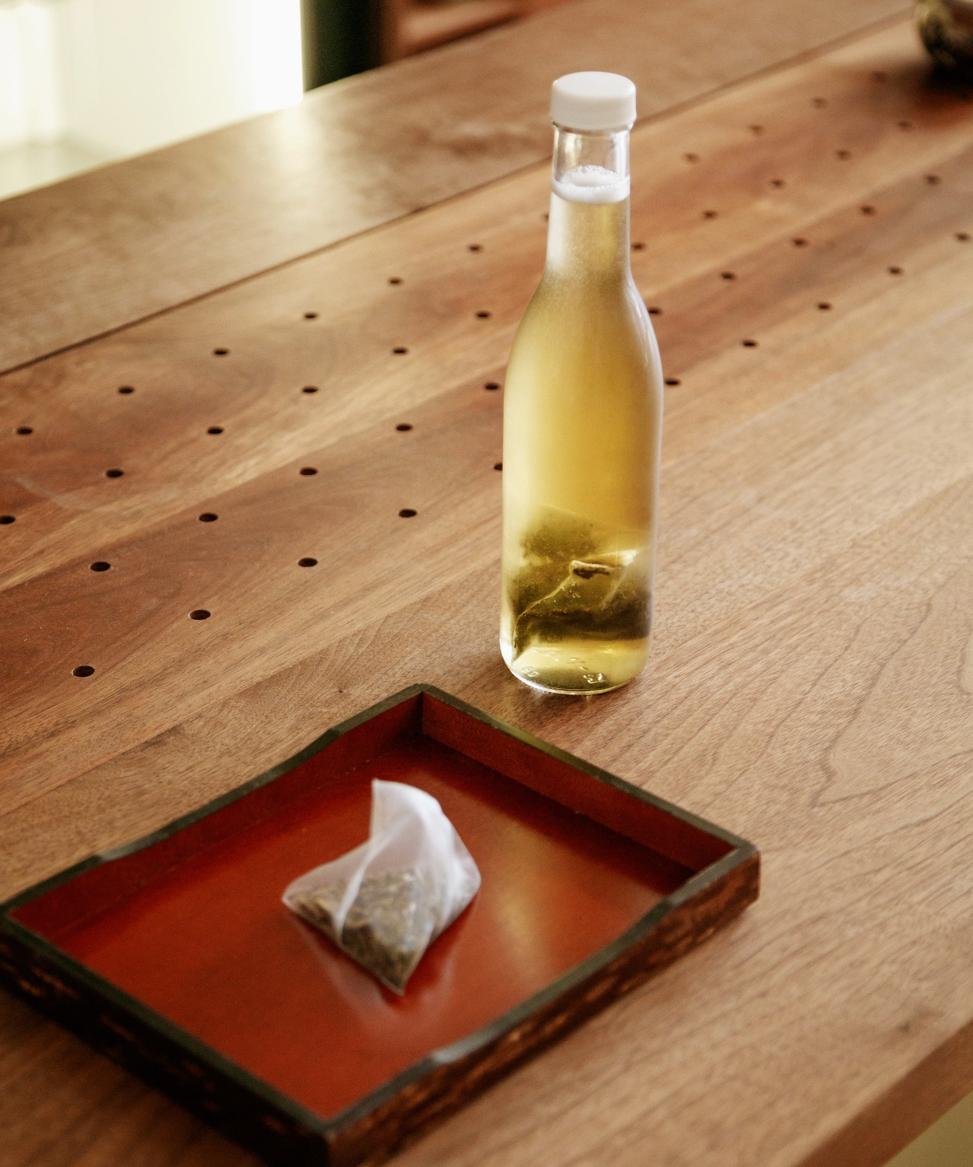 Noma Koshun tea bag on a lacquered tray with a bottle of cold-brewed sparkling hojicha