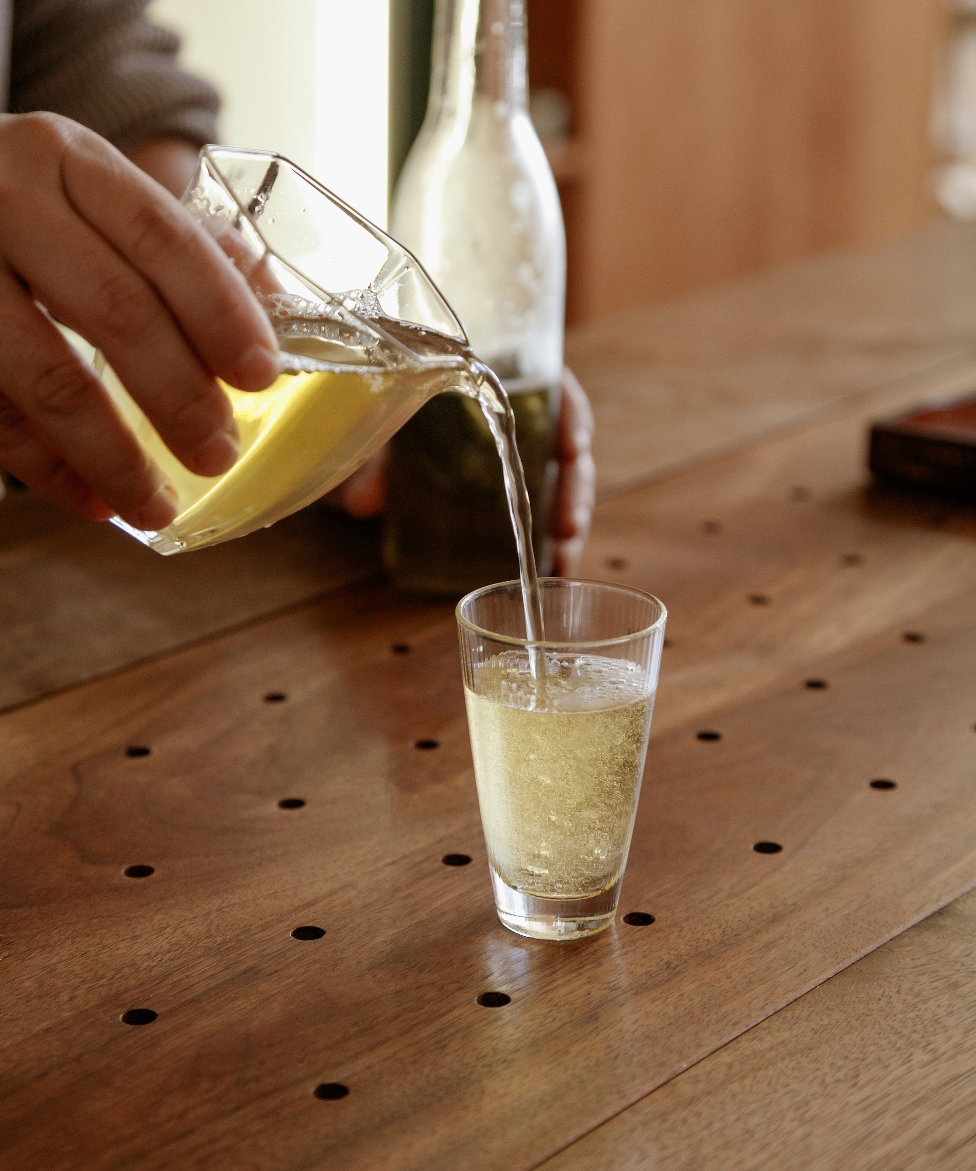 Pouring Noma Koshun hojicha from a glass pitcher into a tall glass, sparkling and refreshing