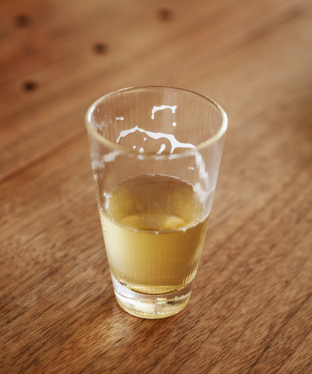 Glass of brewed Noma Koshun sparkling hojicha showing pale golden liquor
