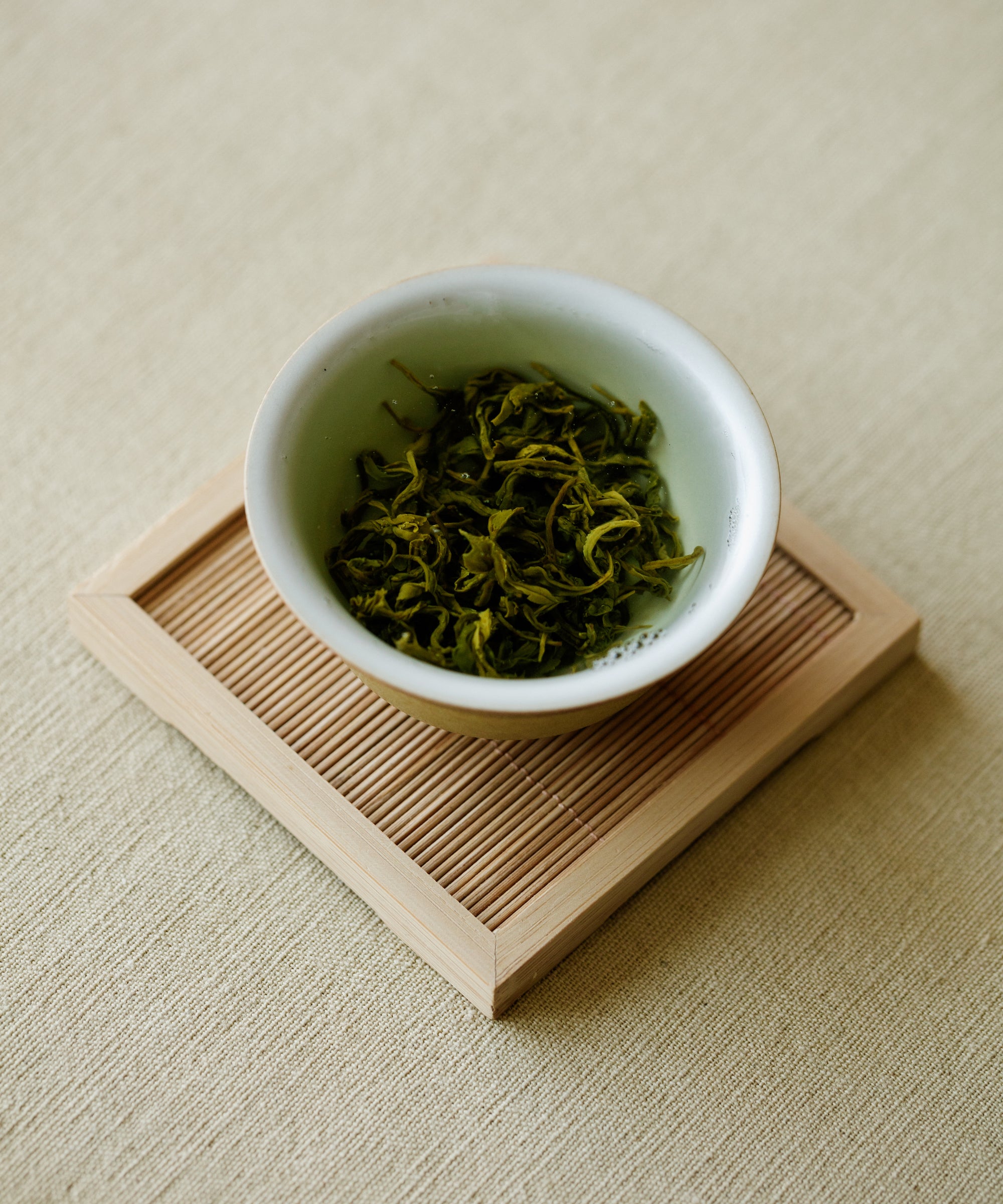 Laoshan Green dry leaves on white dish — charcoal wok pan-fried, ocean-influenced green tea from Laoshan, Qingdao