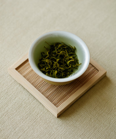 Laoshan Green dry leaves on white dish — charcoal wok pan-fried, ocean-influenced green tea from Laoshan, Qingdao