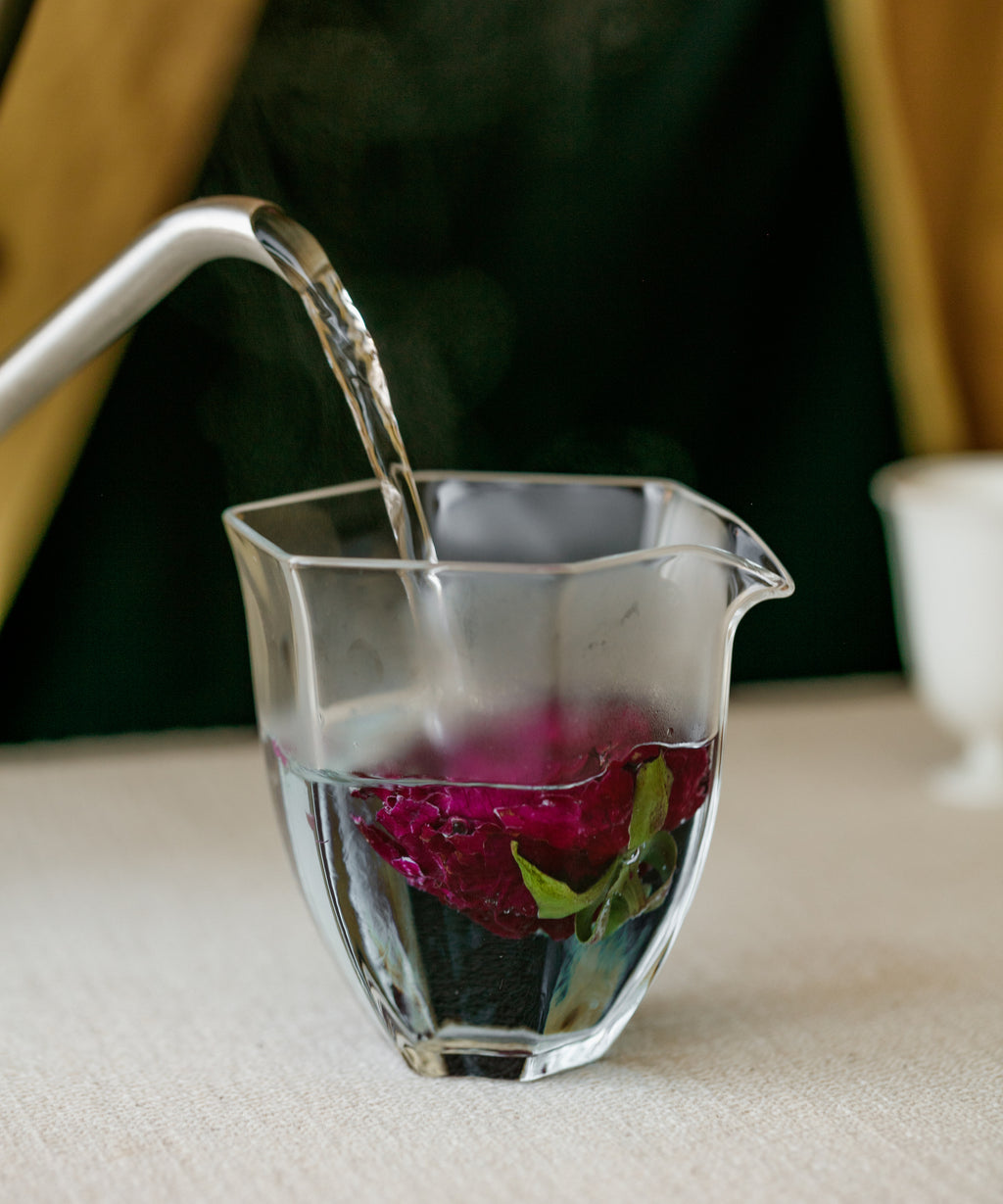 Hot water poured over crimson roses for brewing