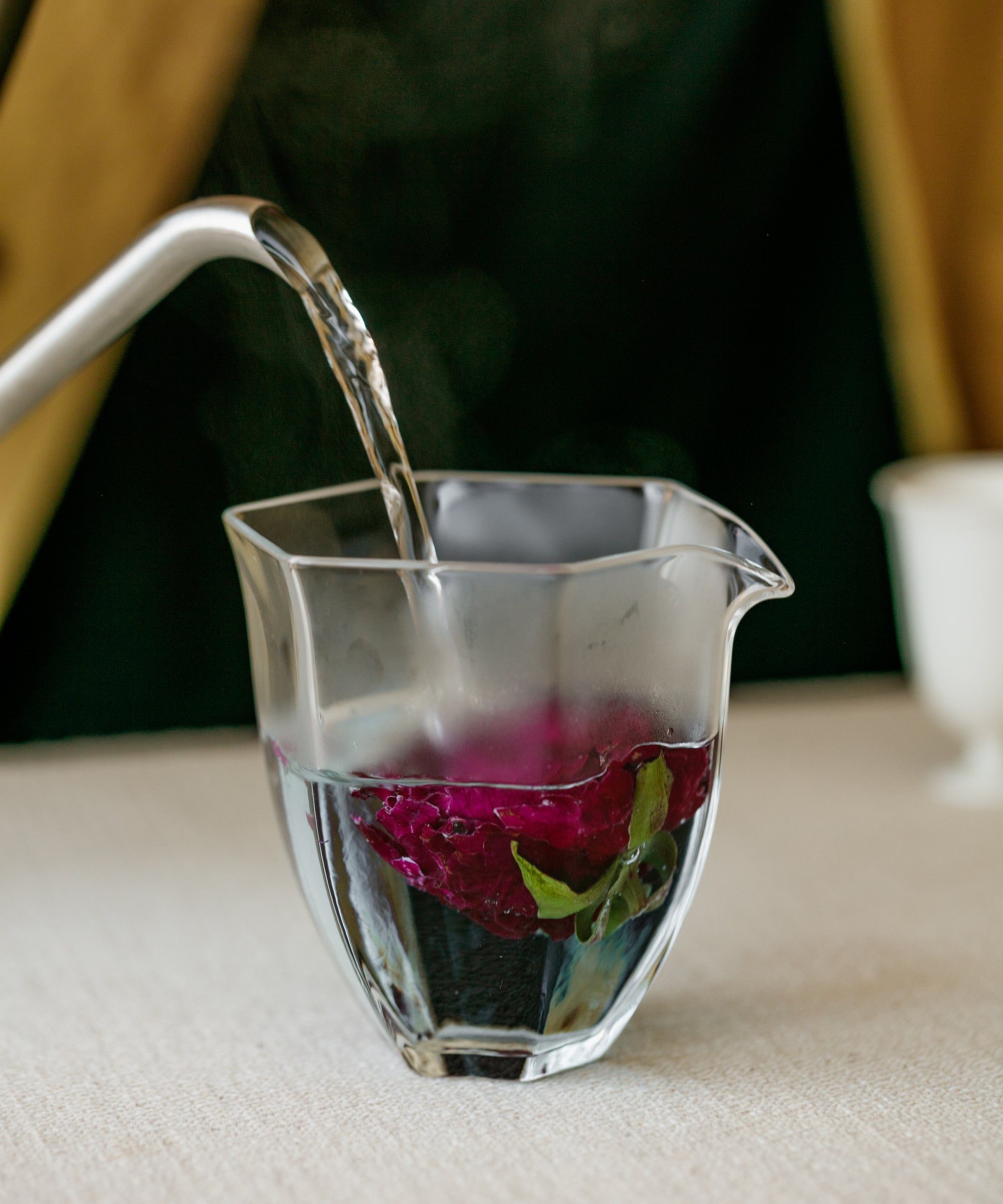 Hot water poured over crimson roses for brewing
