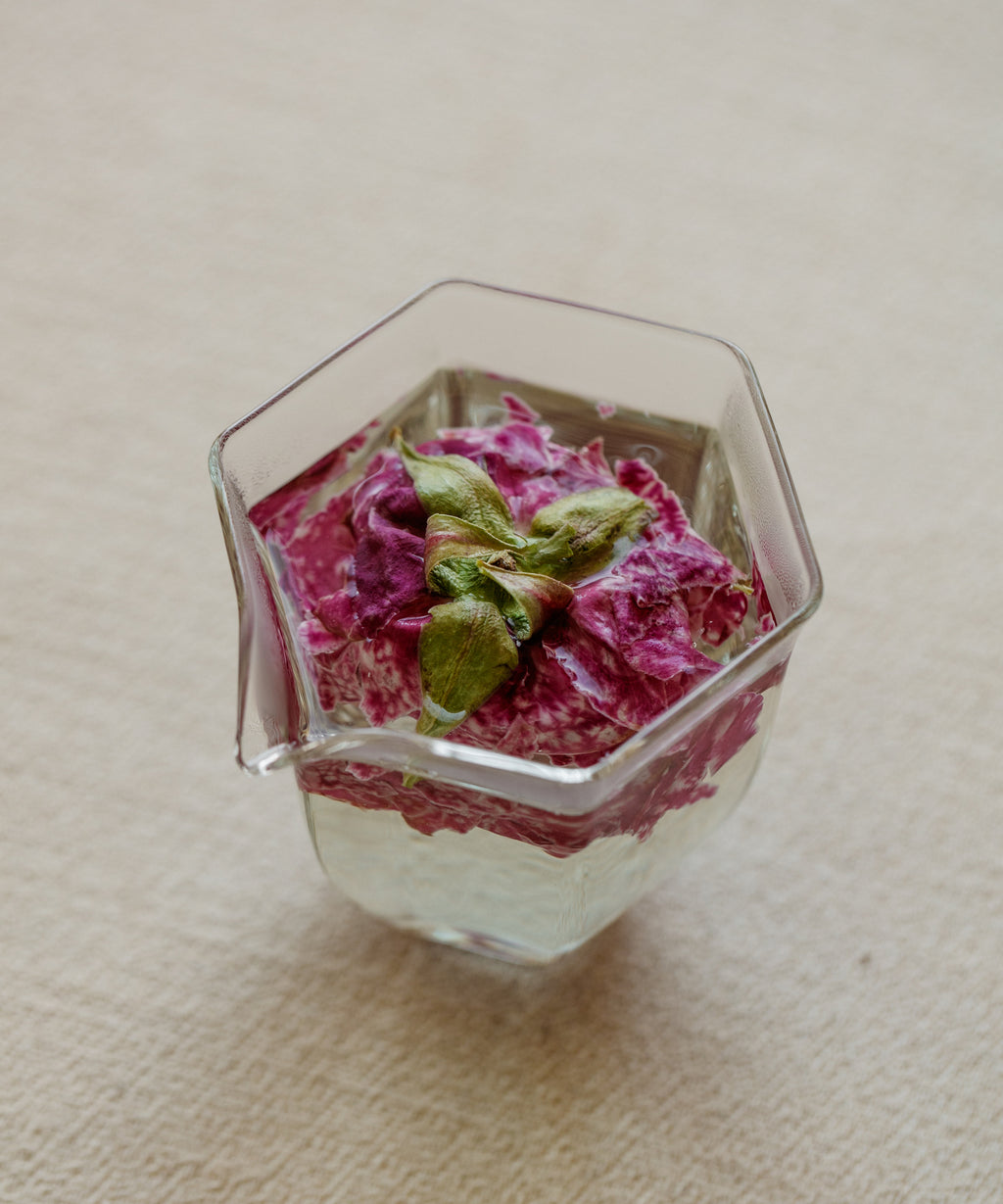Brewed crimson rose tisane showing pink-red liquor in a glass