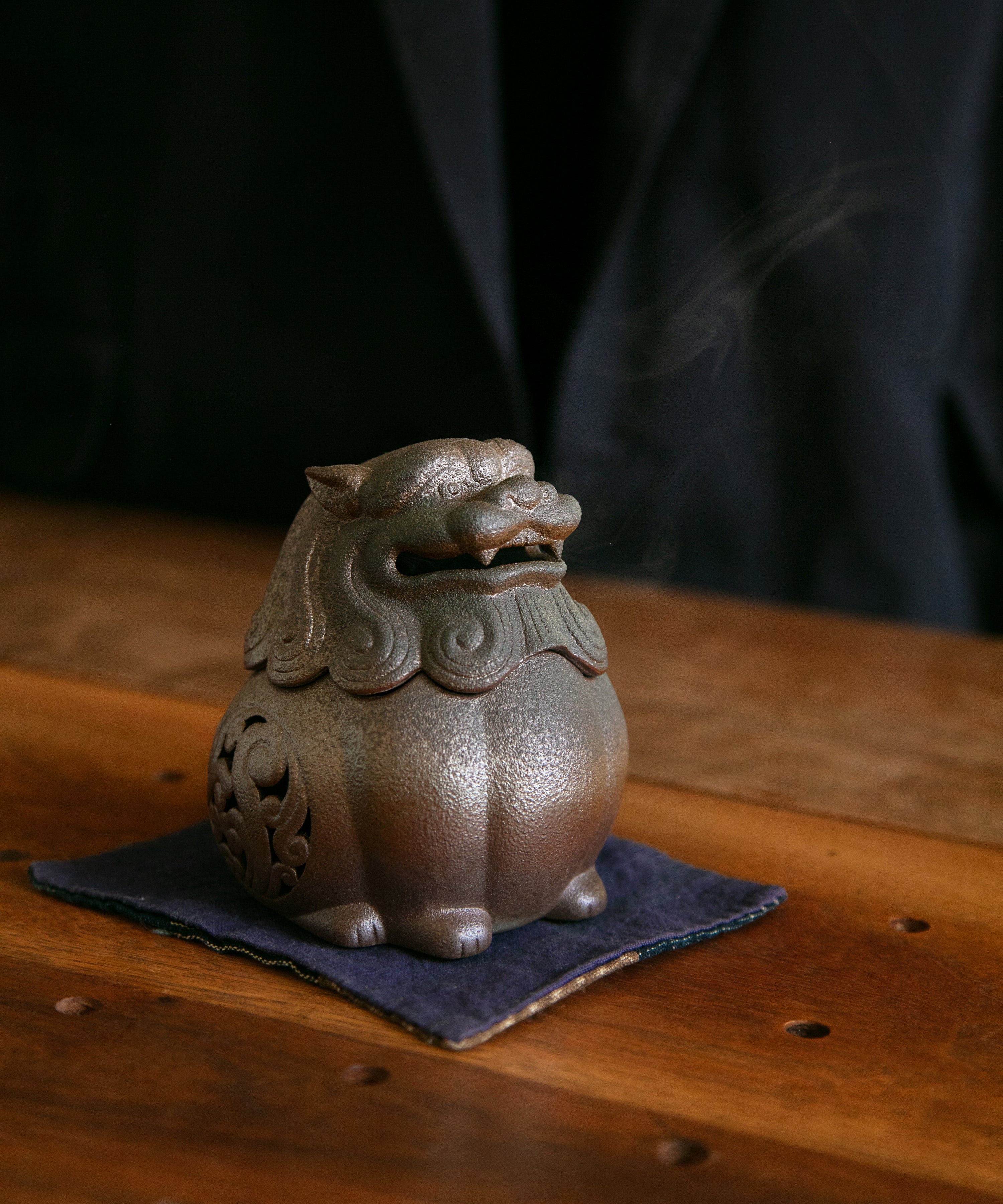 Lit incense in the ceramic lion burner with smoke emerging from the body