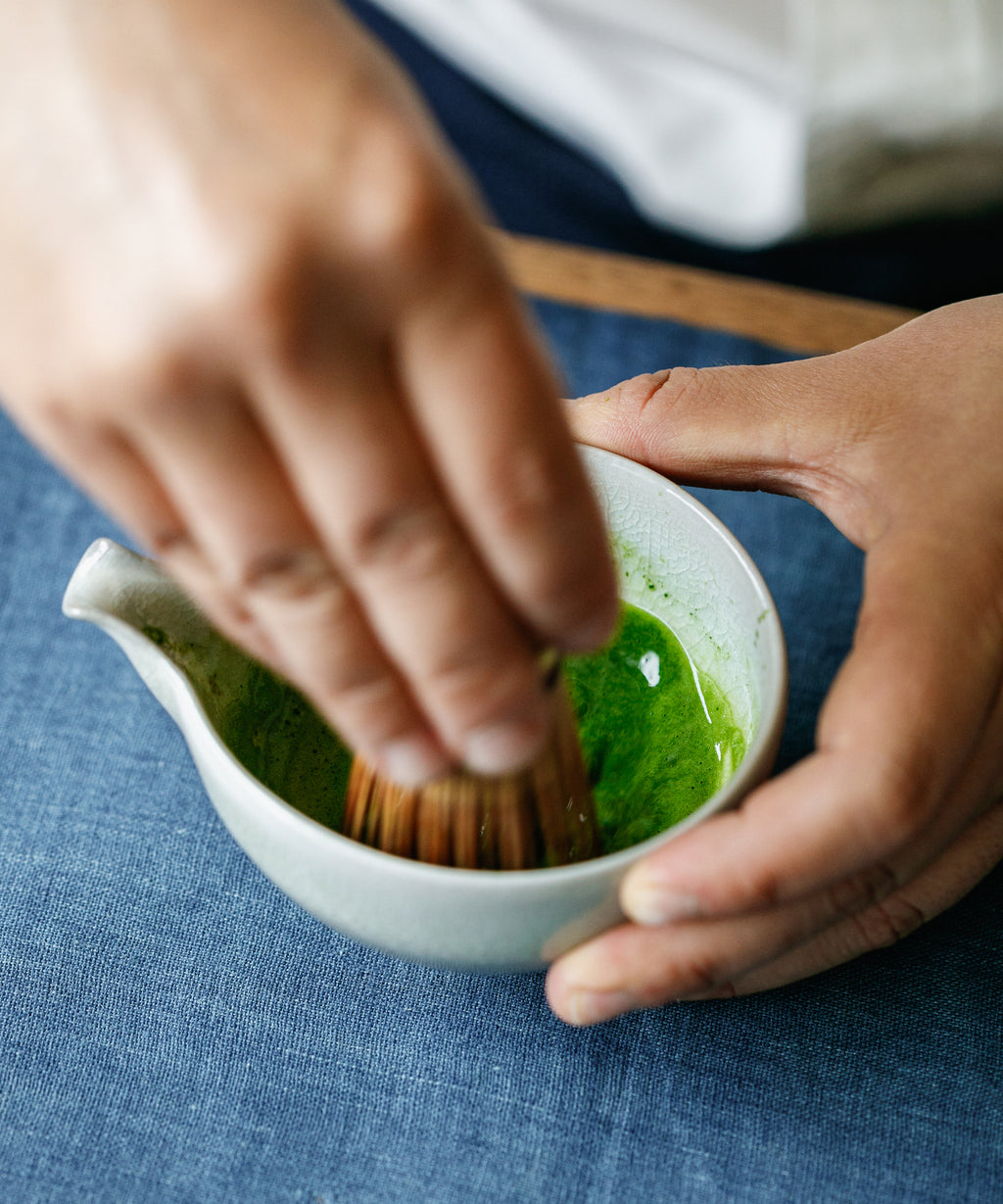 Hand whisking Matcha Yamabuki Japanese matcha with bamboo chasen in white bowl