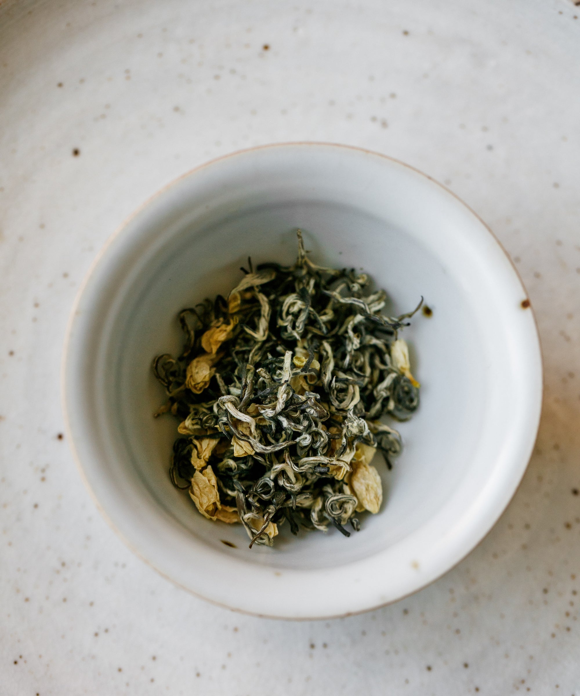 Dry Jasmine Snow Flake tea leaves in a white bowl ready for brewing