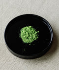 Matcha Hatsumukashi ceremonial powder on black plate — Arita Sansuien first harvest from Uji, Kyoto, binchotan charcoal finished