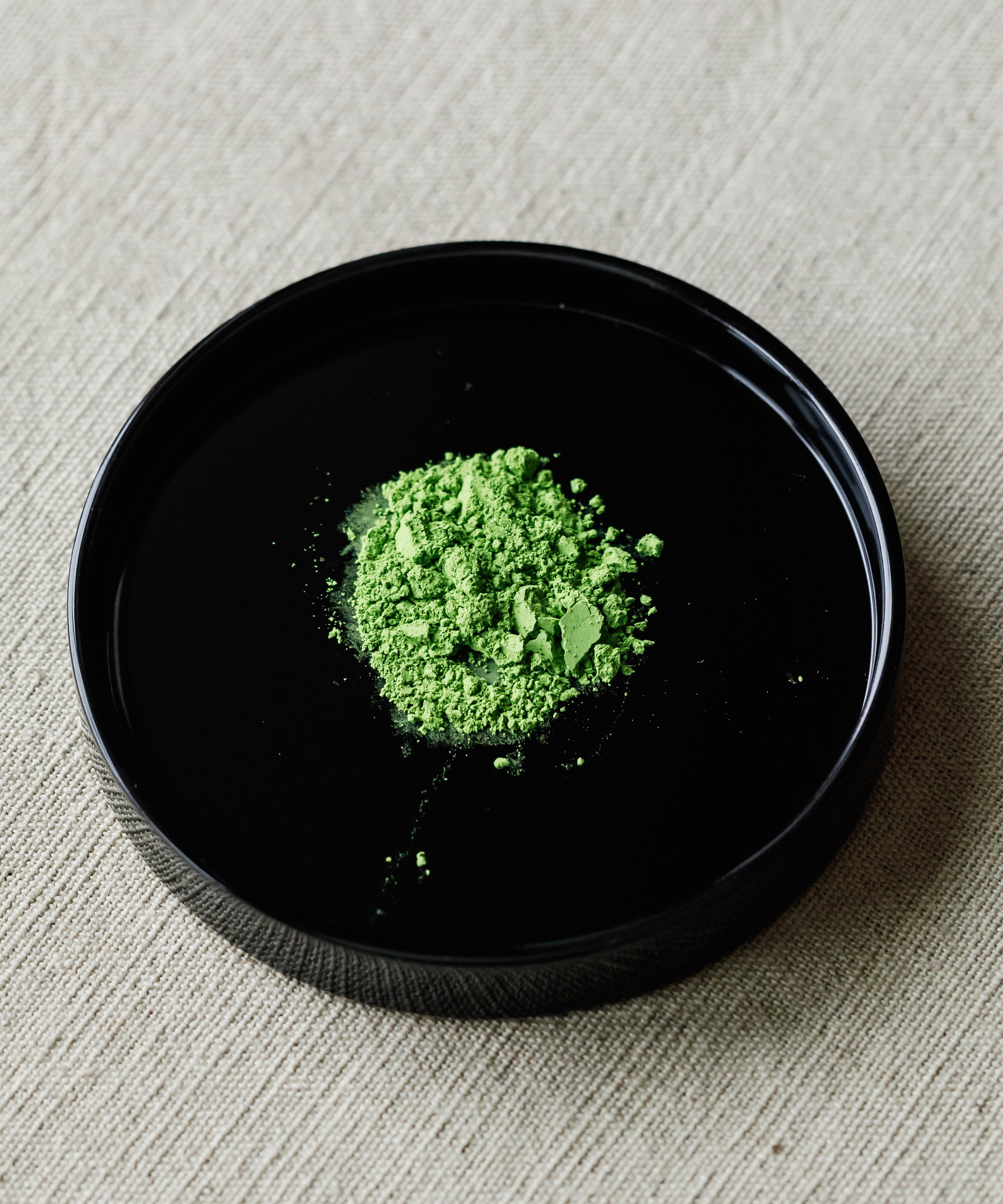 Matcha Hatsumukashi ceremonial powder on black plate — Arita Sansuien first harvest from Uji, Kyoto, binchotan charcoal finished