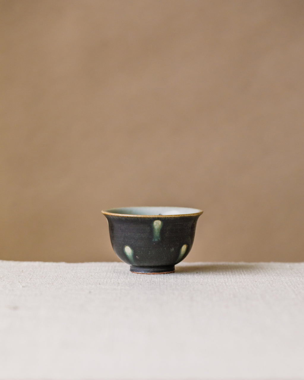 Cup Black Peacock, handcrafted tea cup by Wang Xinghua, Jingdezhen, matte black with green-ringed white spots