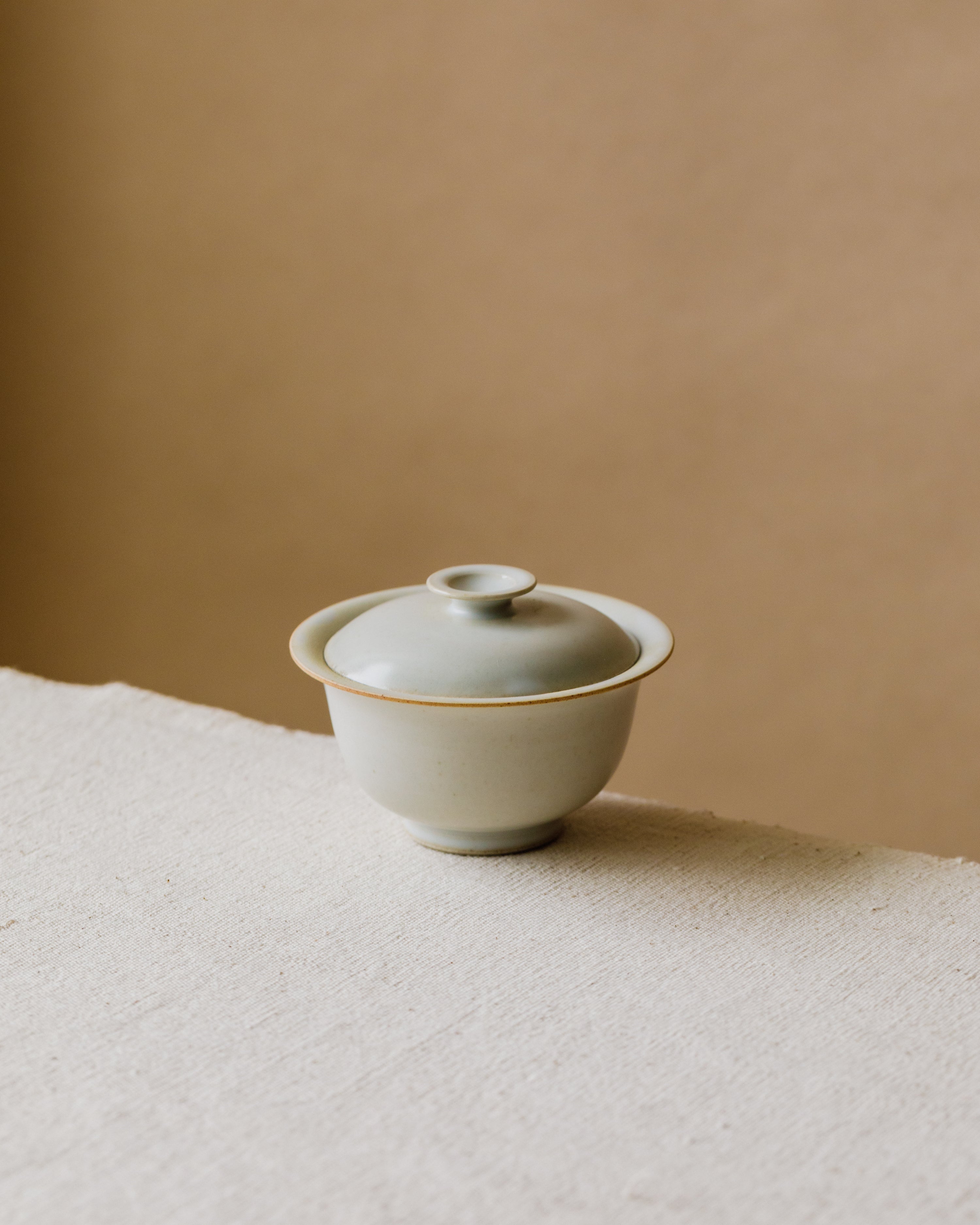 Gaiwan Sateen Porcelain in hand, warm white glaze flecked like vanilla, Wang Xinghua gongfu teaware