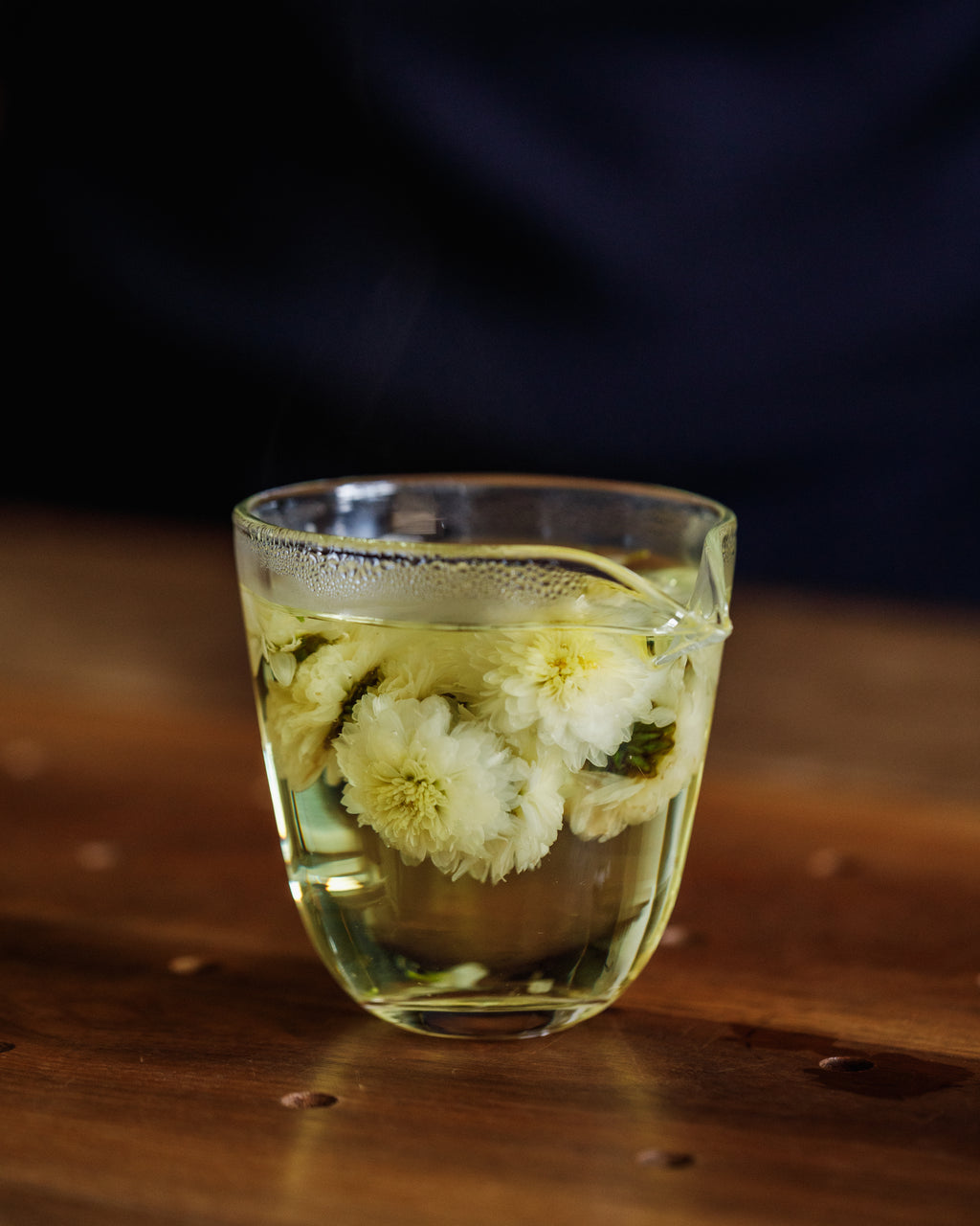 Chrysanthemum flowers blooming in hot water, releasing golden liquor