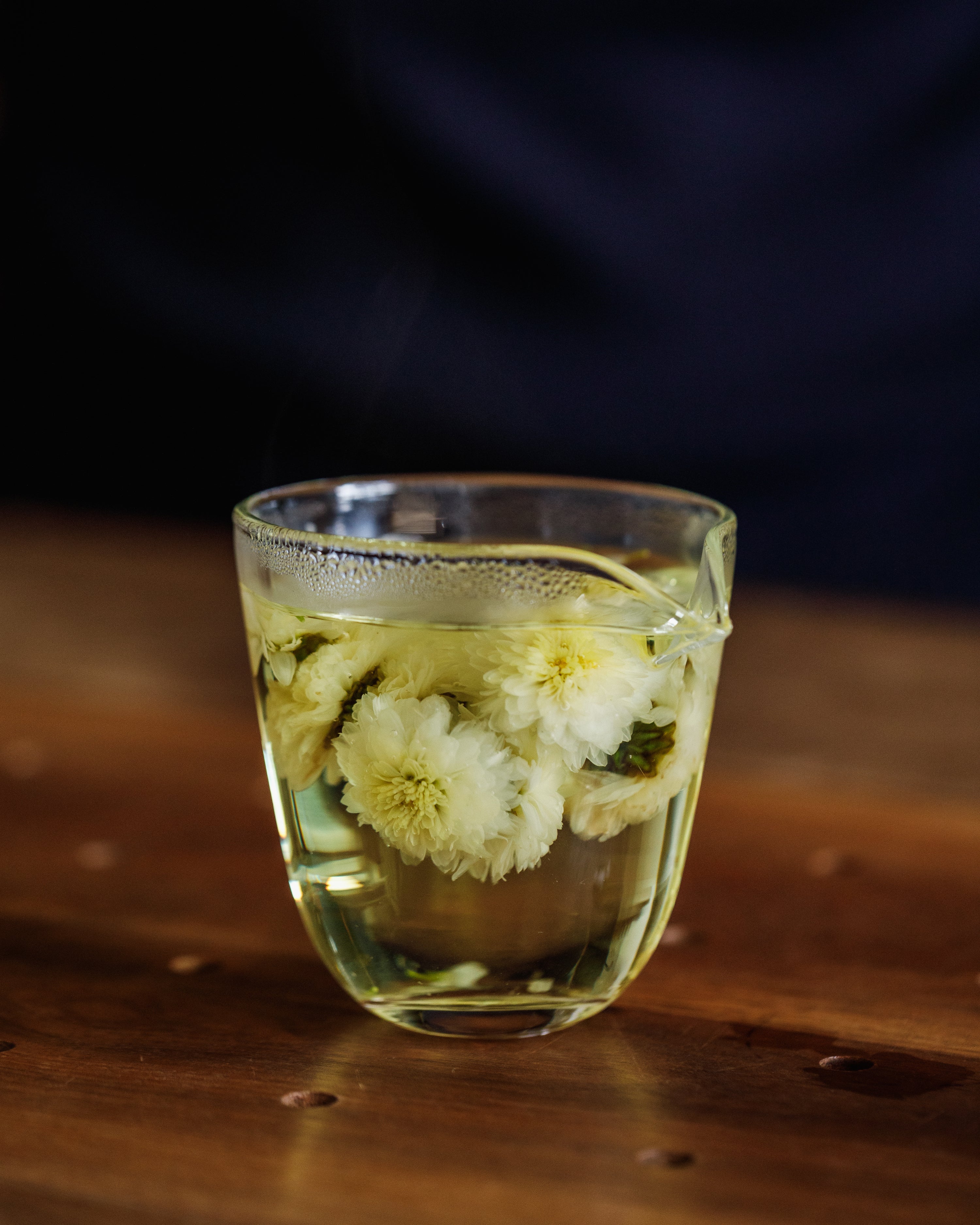 Chrysanthemum flowers blooming in hot water, releasing golden liquor