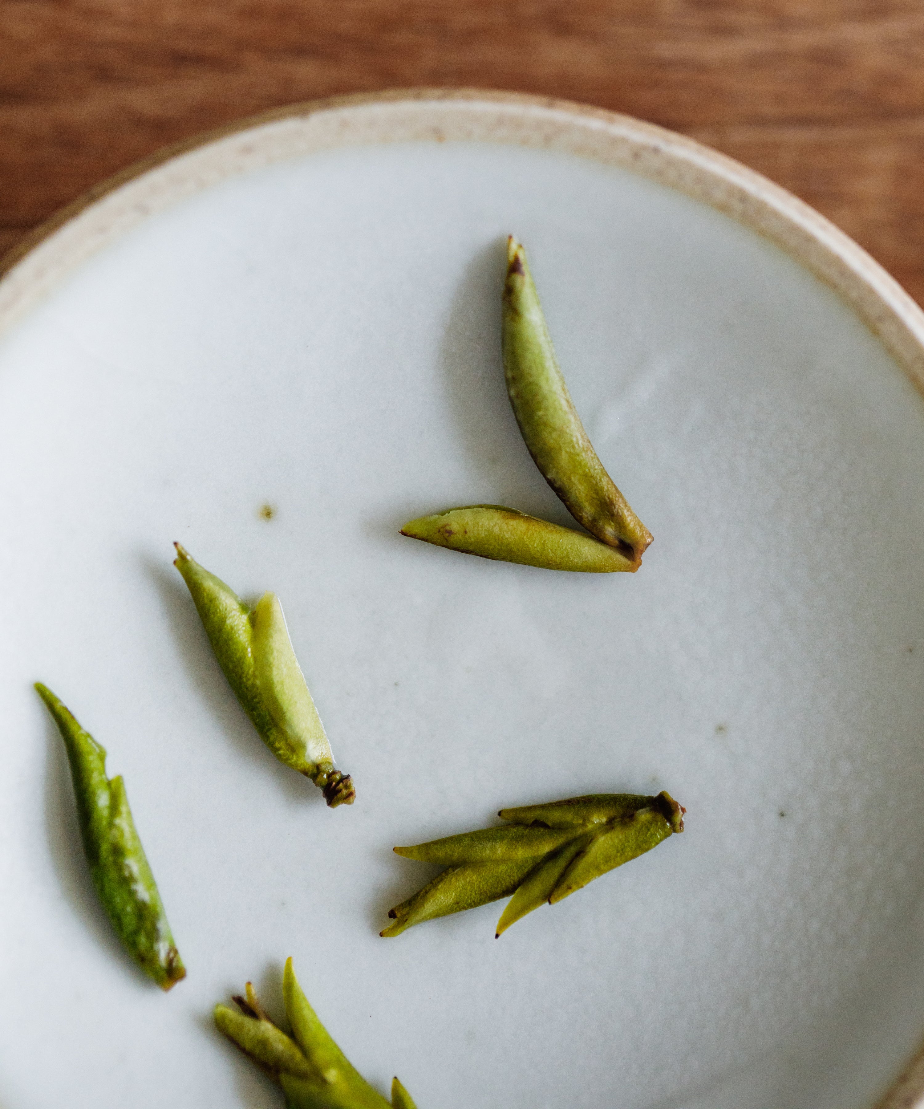 Daxueshan wild pu'erh shoots wet leaves after brewing — dense green buds with purple streak, Jinggu, Yunnan