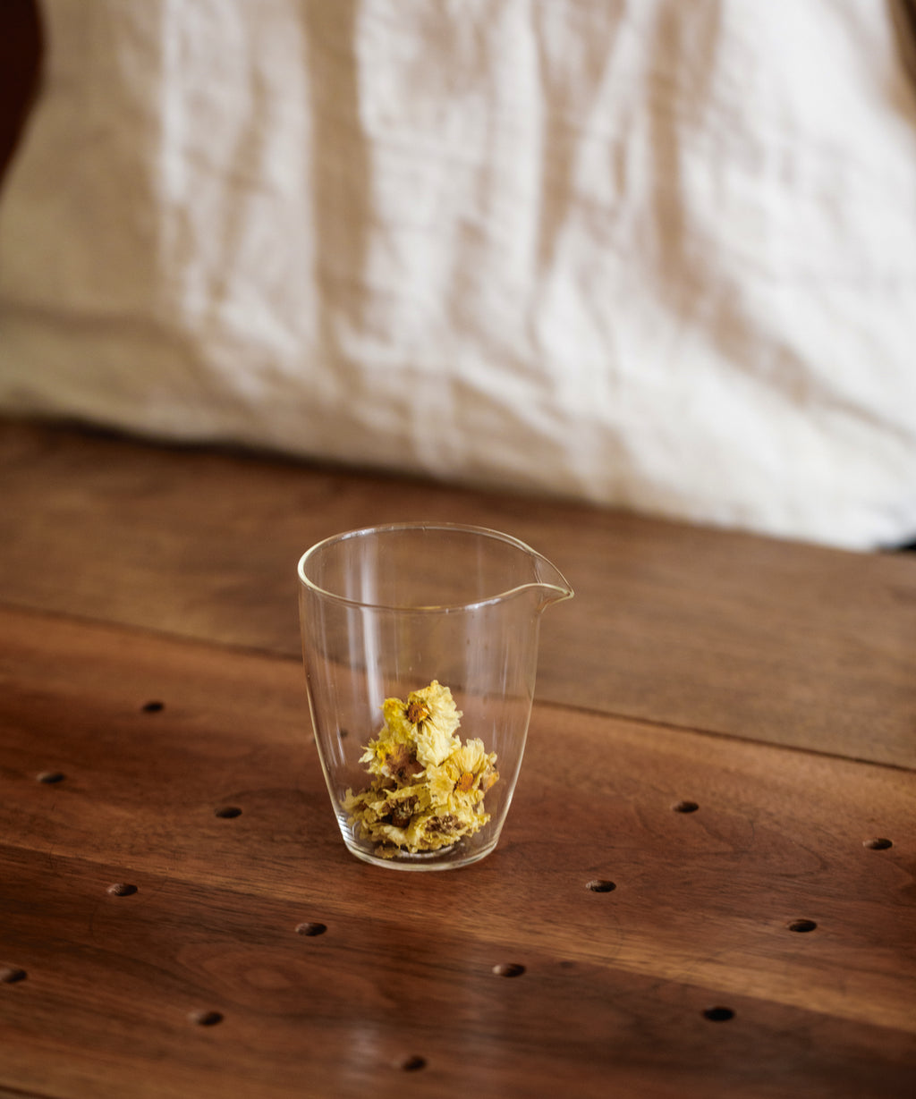 Brewing Silk Chrysanthemum Cake in a glass pitcher, pressed flowers expanding in hot water