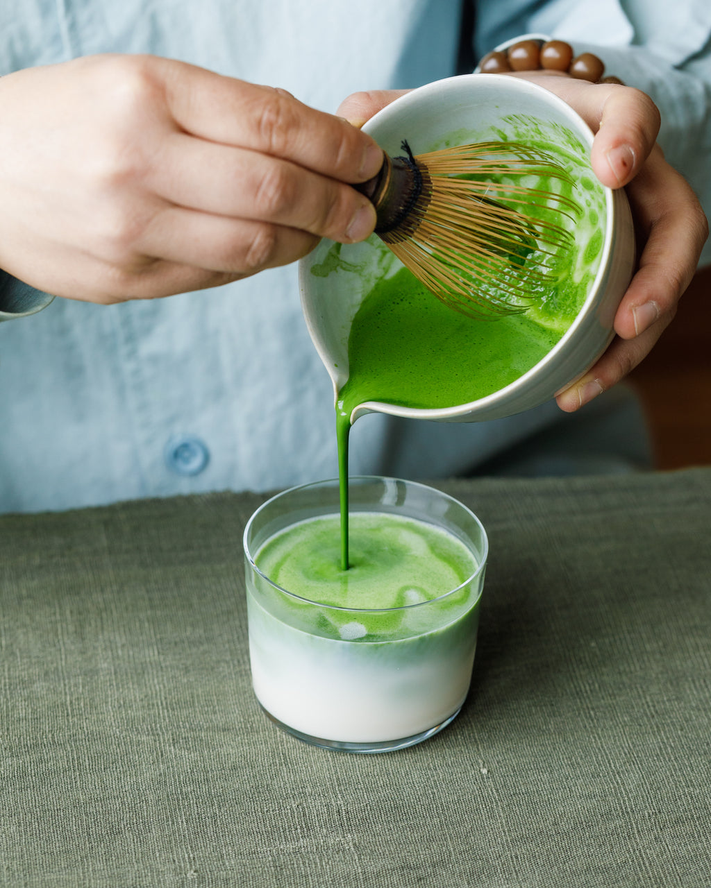 Pouring Matcha Hikari latte into glass with steamed milk