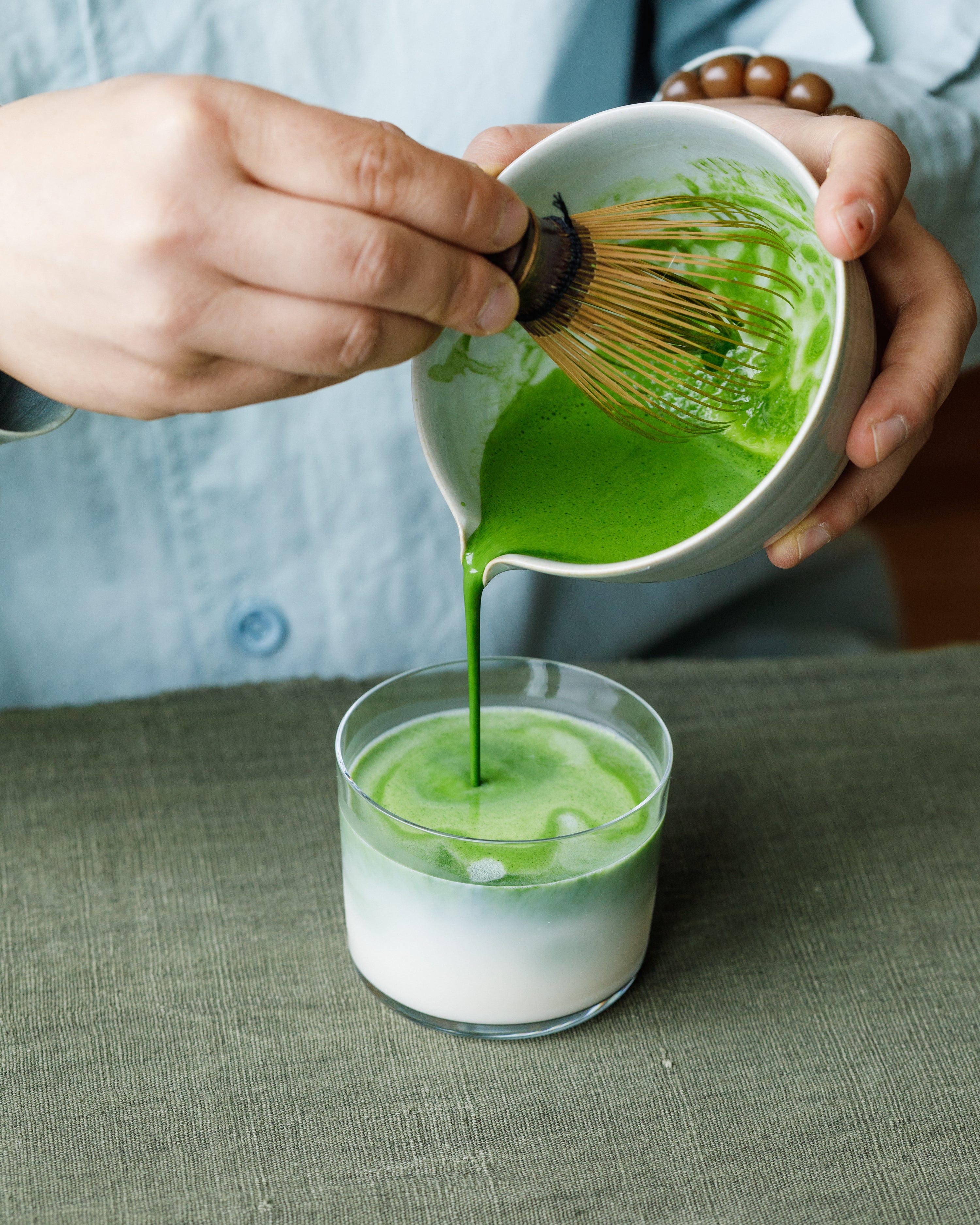 Pouring Matcha Hikari latte into glass with steamed milk