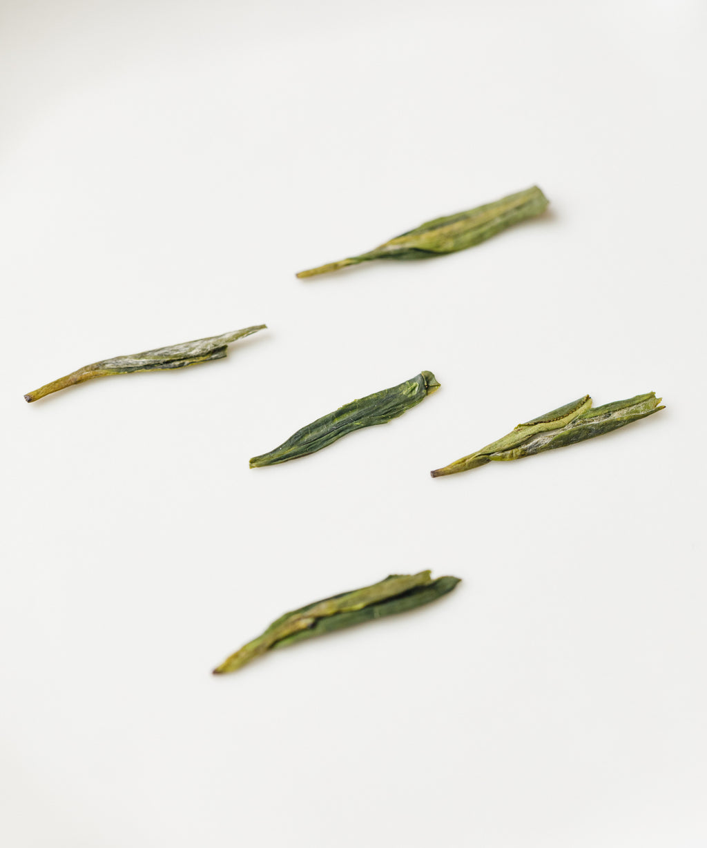 Dry Master Tang's Dragonwell Longjing showing the flat broad leaves from hand pan-frying