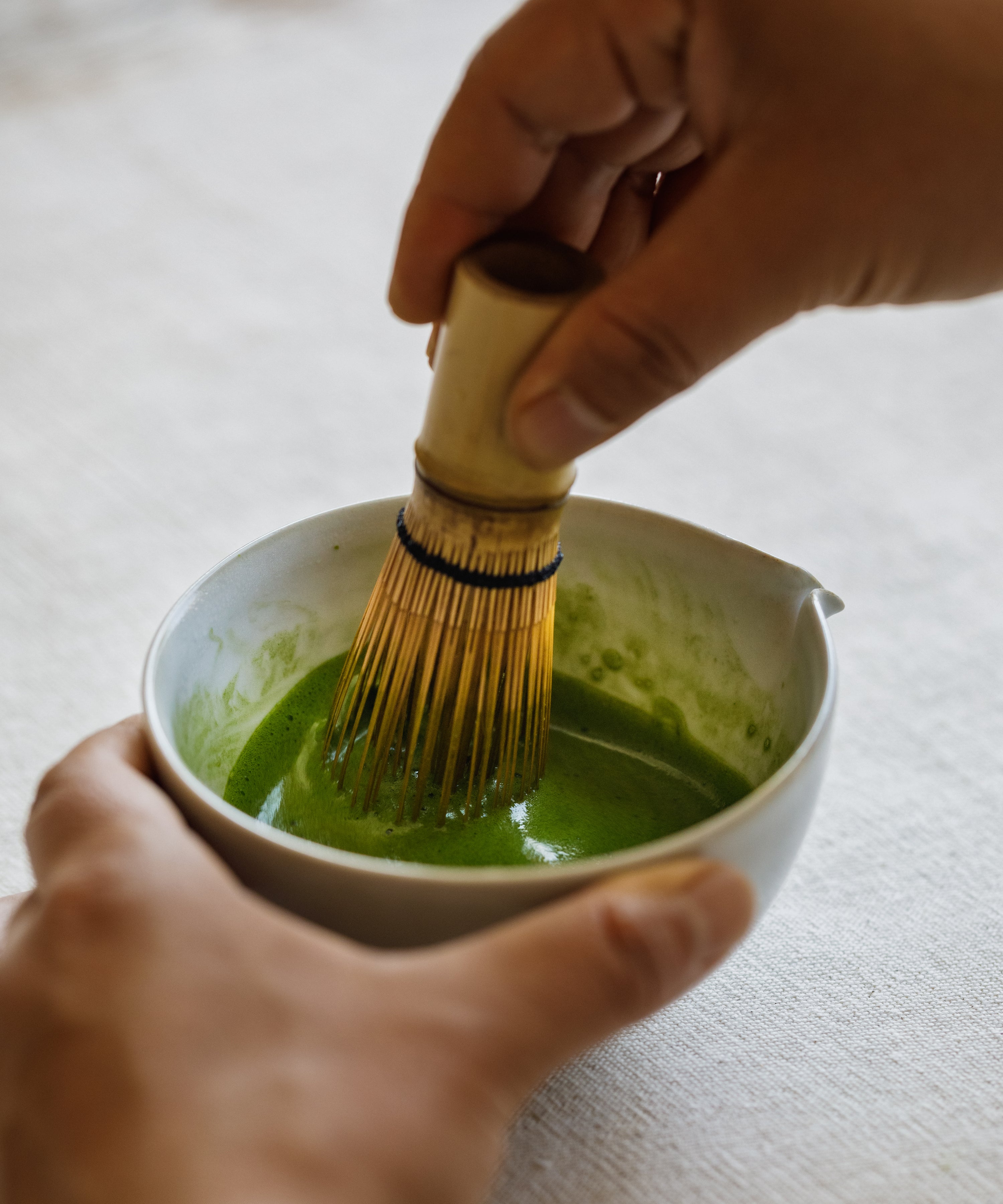 Whisking Seimei matcha with a bamboo chasen in a white ceramic bowl