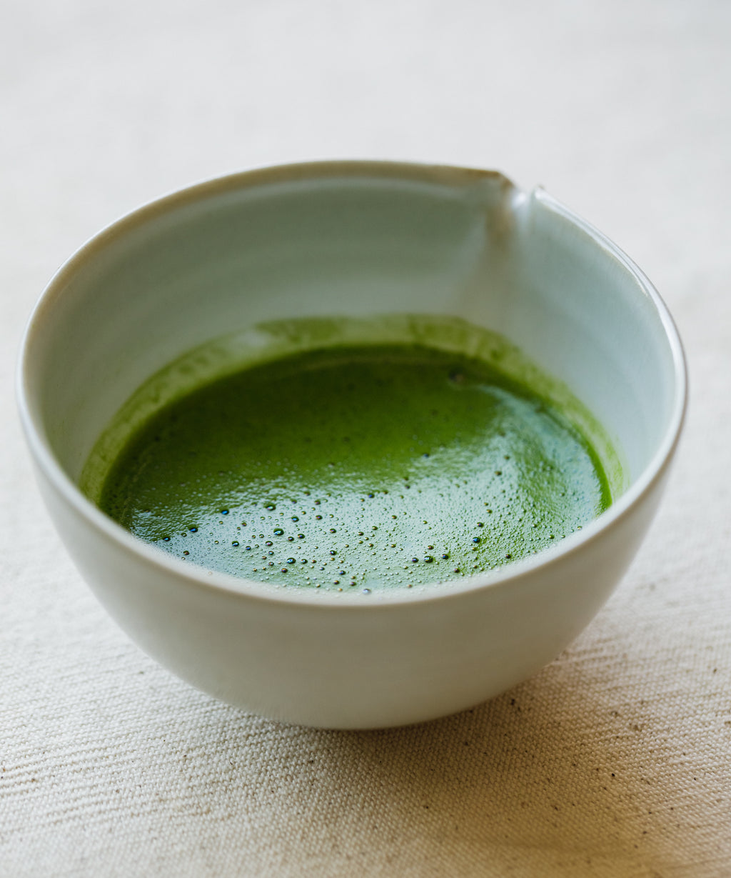 Pouring Seimei matcha into a glass for latte preparation