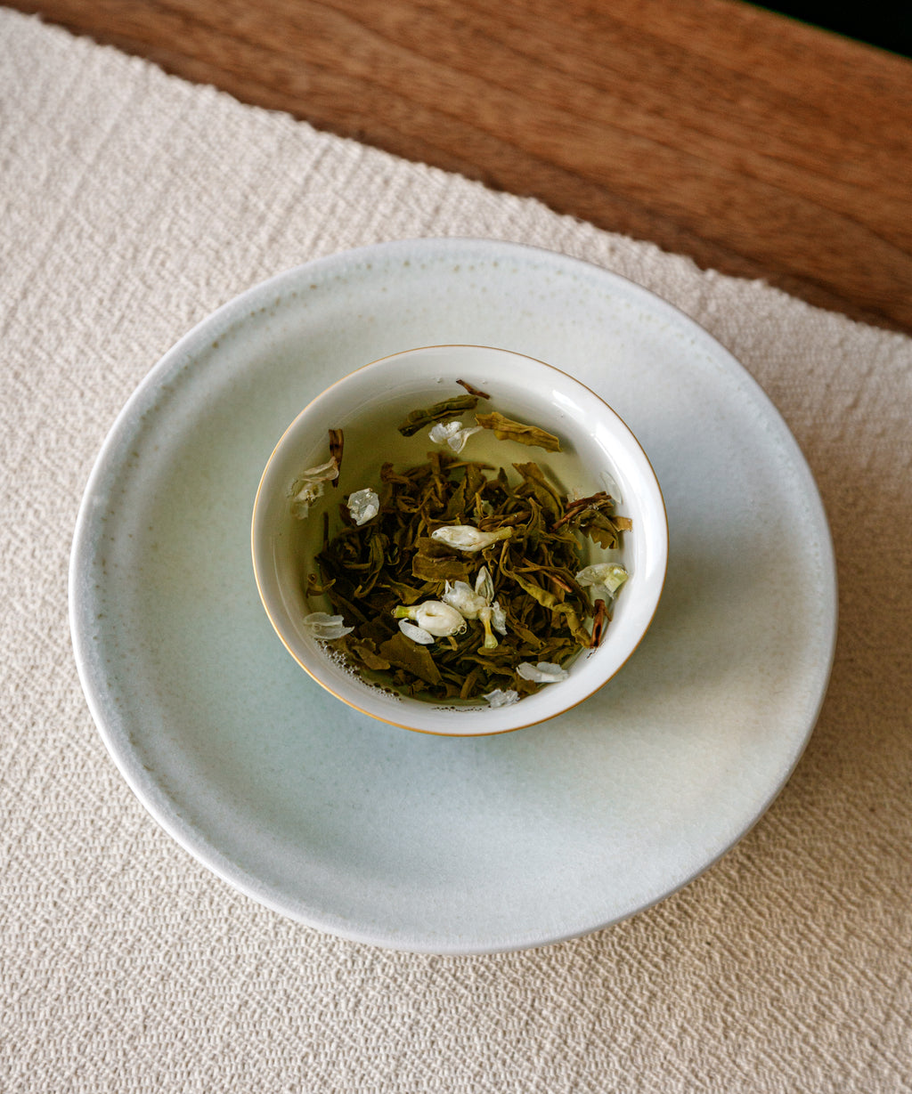 Brewing Jasmine Jade Tips — hot water over white flowers and darkened green Maofeng leaves