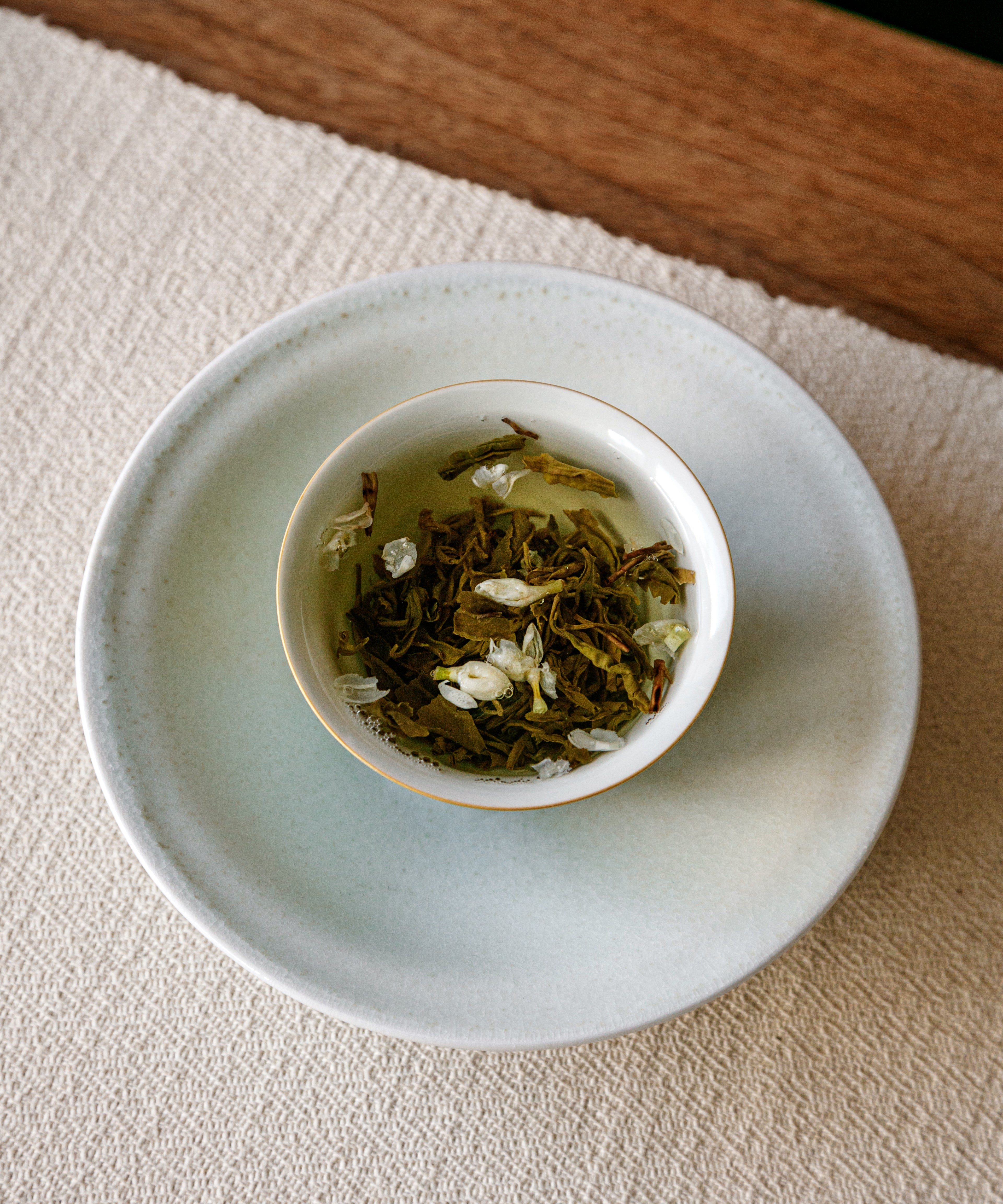 Brewing Jasmine Jade Tips — hot water over white flowers and darkened green Maofeng leaves