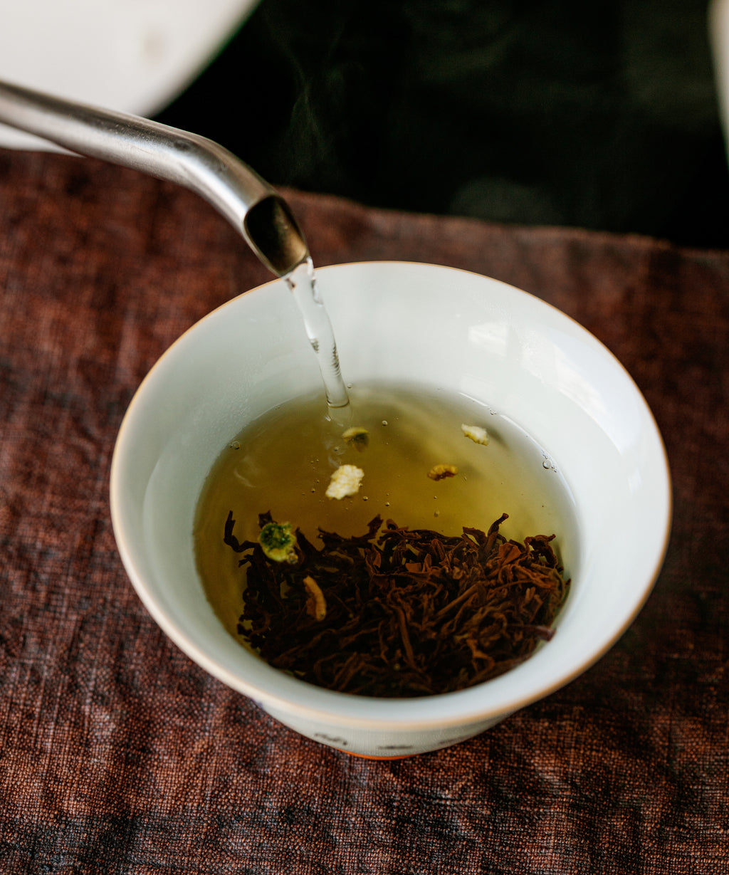 Hot water poured over Yuzu & Gold Guanyin leaves in a white gaiwan