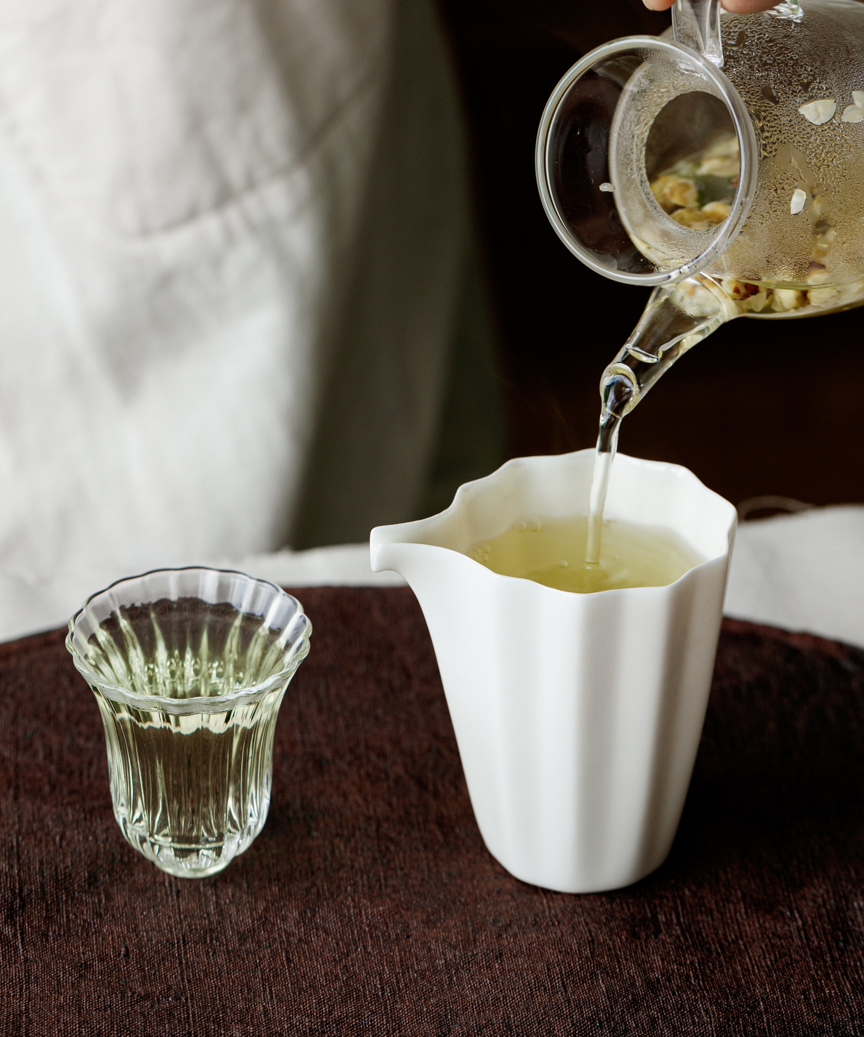 Brewed plum blossom infusion poured from a white gaiwan into a small glass cup